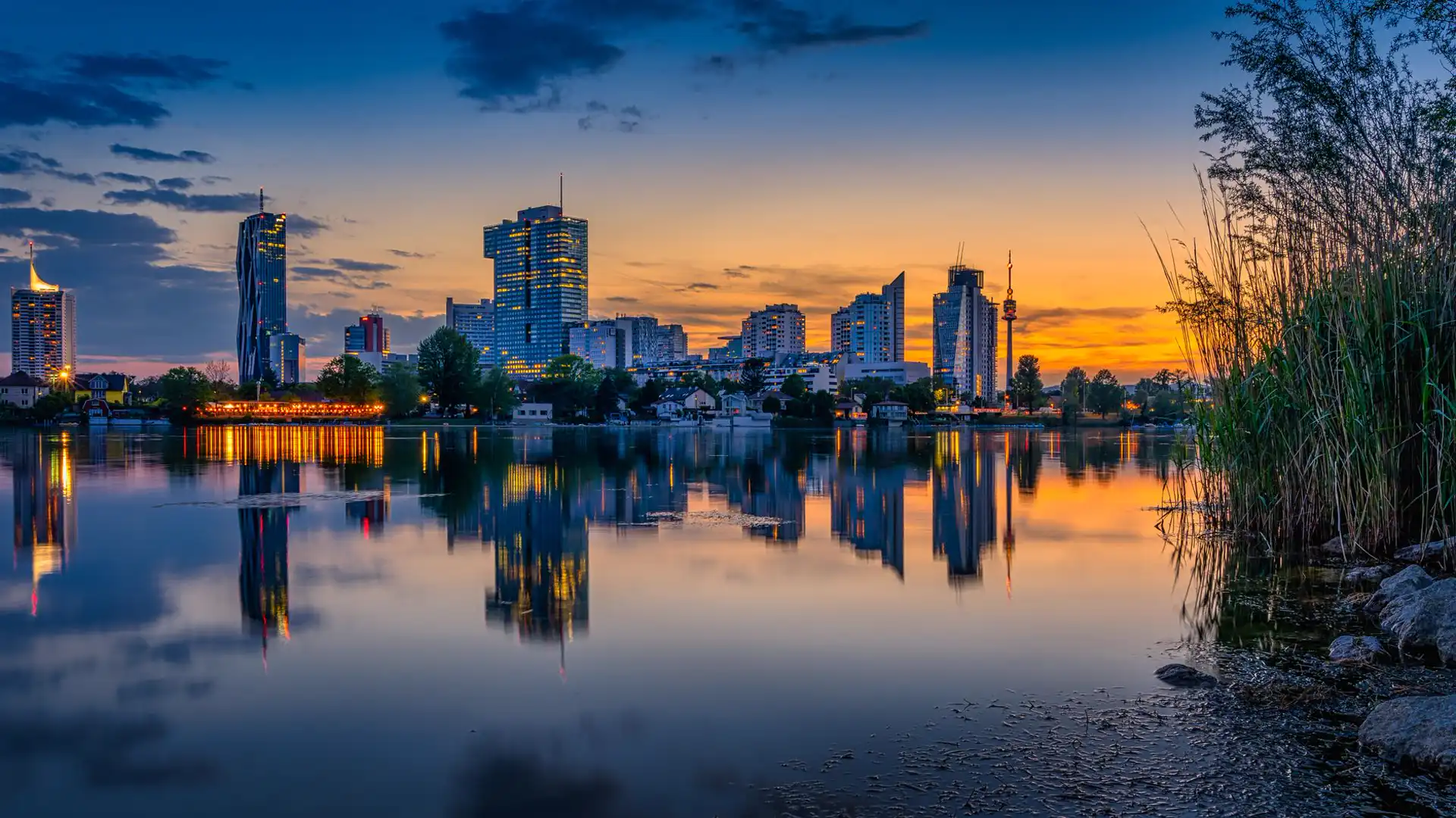 Vienna at sunset, the Donau City skyline reflected in the water.